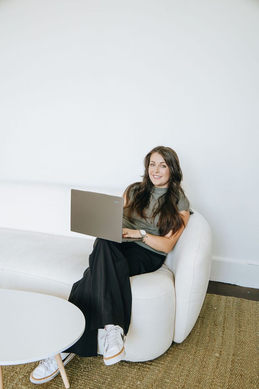 Emily smiling on a white sofa with a laptop