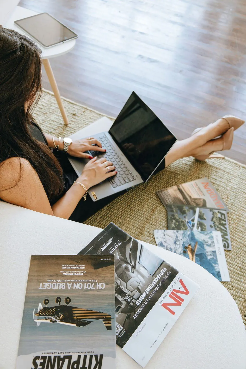 Overhead view of Emily working on a laptop surrounded by aviation magazines