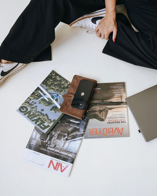 FLYING, AvBuyer, and AIN magazines laid out with a planner, phone, and laptop