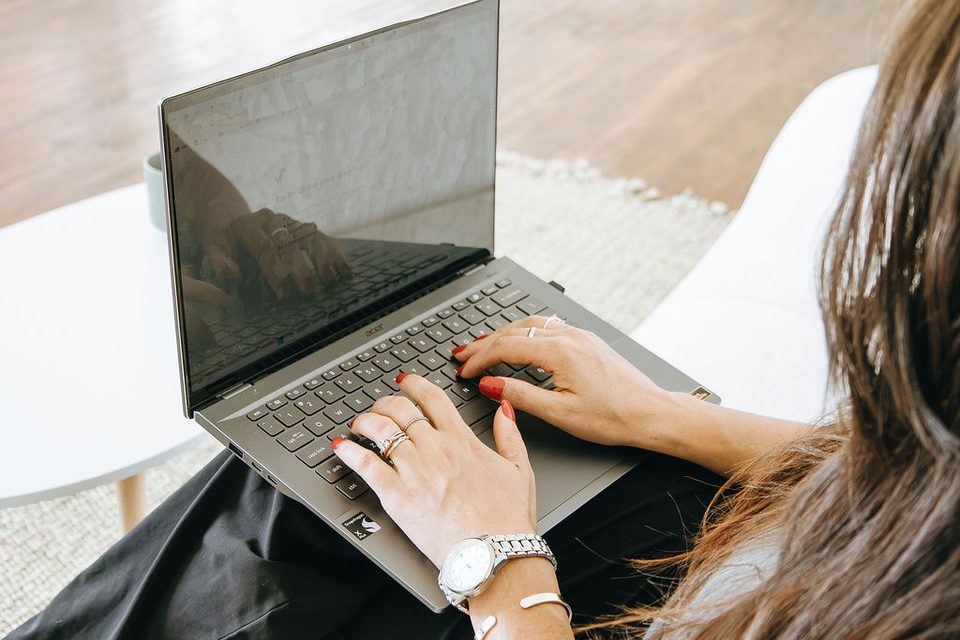 Emily typing on a laptop, seen over her shoulder
