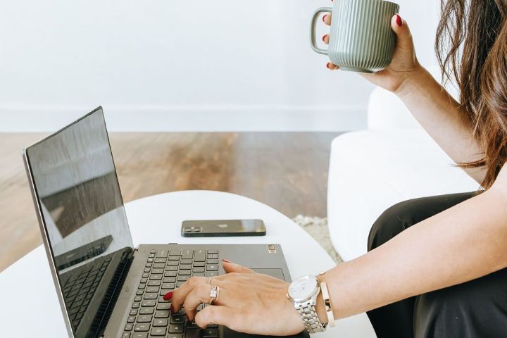 Emily typing on a laptop with a coffee mug in hand